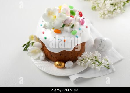 Traditioneller Osterkuchen mit Streuseln, Jelly Beans, Marshmallows und dekorierten Eiern auf einem weißen Tisch Stockfoto