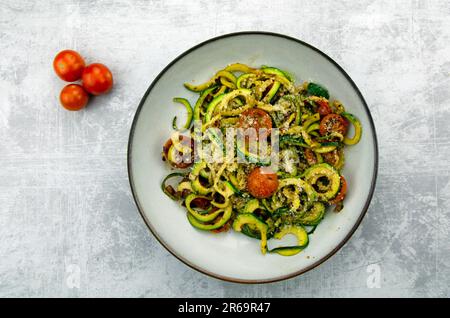 Zucchini-Pasta mit Parmesan und Tomate in einer Schüssel auf Marmorhintergrund Stockfoto