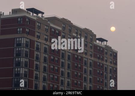 New York, Usa. 07. Juni 2023. NEW YORK, NEW YORK - 07. JUNI: Orange Sun Sonnenuntergang über Astoria während starker Rauch von kanadischen Waldbränden die Skyline von New York City am 7. Juni 2023 im Stadtteil Queens von New York City bedeckt. New York stand Dienstagabend an der Spitze der Liste der am meisten verschmutzten Großstädte der Welt, da die Ostküste weiterhin mit Rauch von den Bränden bedeckt ist. Die Stadt gab eine Luftqualitätsempfehlung heraus, in der alle Bürger dringend aufgefordert wurden, sich im Haus zu halten. Kredit: SOPA Images Limited/Alamy Live News Stockfoto