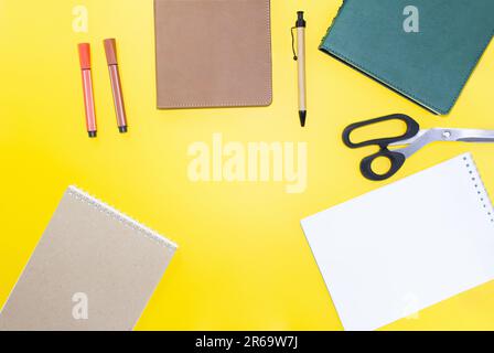 Zurück in die Schule. Unterricht im flachen Bett. Geschäftsaufbau. Modell, Notizblöcke, Stift, Marker, Schere auf gelbem Hintergrund. Arbeitsplatz. Speicherplatz kopieren Stockfoto