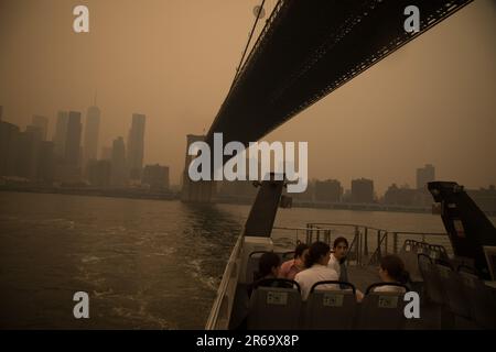 New York, USA. 7. Juni 2023. Passagiere fahren am 7. Juni 2023 mit der Fähre auf dem East River in New York, USA. Rauch von wütenden Waldbränden in Kanada hat in einer Reihe von US-Bundesstaaten Luftqualitätswarnungen ausgelöst, wobei der Himmel über New York City am Mittwochnachmittag schnell verdunkelt und New York State Governor Kathy Hochul die Verschlechterung der Luftqualität als „eine Notkrise“ bezeichnet. New Yorker leiden unter dem Rauch des kanadischen Wildfire Credit: Michael Nagle/Xinhua/Alamy Live News Stockfoto