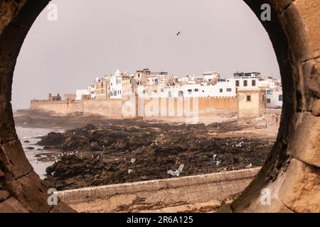 Sehen Sie sich die Befestigungsanlagen im Hafengebiet an, mit der Stadt Essaouira im Hintergrund. Essaouira, bis in die 1960er Jahre als Mogador bekannt, ist eine Hafenstadt Stockfoto