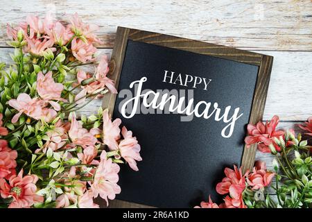 Fröhlicher Januar-Text an der Tafel mit Blumenstrauß Stockfoto