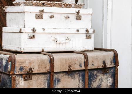 Ein Haufen alter Koffer auf rustikalem Holzparkettboden in schäbigen, schicken Innenräumen im Landhausstil der Provence Stockfoto