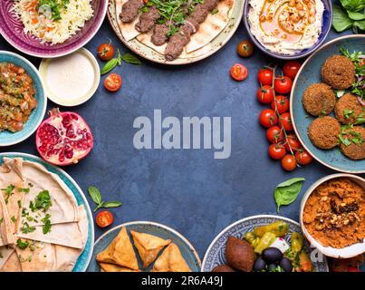 Nahöstliche oder arabische Gerichte und verschiedene Meze auf rustikalem Betonhintergrund. Fleischkebab, Falafel, baba Ganoush, Hummus, Sambusak, Reis, Tahini Stockfoto