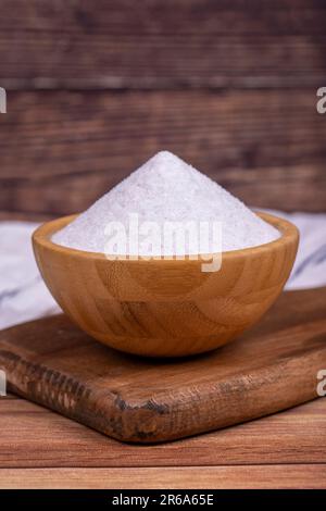 Natürliches nicht jodiertes Mahlsalz aus Minarettkristall auf Holzhintergrund. Gemahlenes Steinsalz in einer Holzschüssel. Schließen Stockfoto