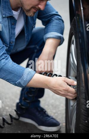 Mann, der den Luftdruck im Autoreifen prüft Stockfoto