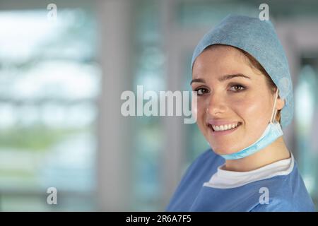 Glückliche Krankenschwester lächelt hinter der Chirurgenmaske Stockfoto