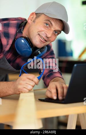 Handwerker, der in der Werkstatt einen Laptop verwendet Stockfoto