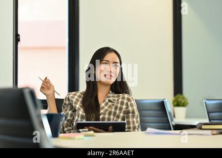 Aufnahme der weiblichen Führungskraft der Millennials, die am Besprechungstisch sitzt und mit ihrem Kollegen spricht Stockfoto