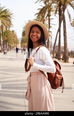 Porträt einer afroamerikanischen Frau, die in ihren Strandferien Tourismus macht und lächelnd in die Kamera schaut. Stockfoto