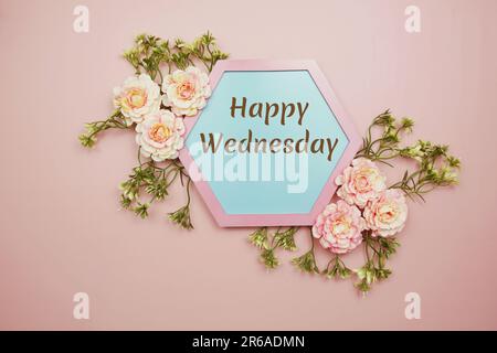 „Happy Wednesday“-Schriftzug mit Blume auf pinkfarbenem Hintergrund Stockfoto
