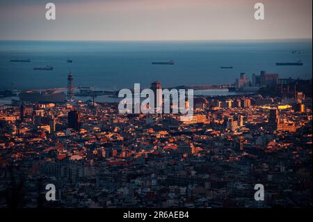 Blick aus der Vogelperspektive von Barcelona bei Sonnenuntergang, mit dem Mittelmeer, dem Hafen von Barcelona, der Skyline der Stadt und Frachtschiffen entlang der Küste Stockfoto