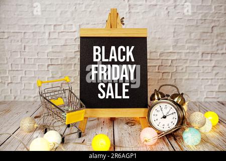 Black Friday Sale Textnachricht mit Wecker und Einkaufswagen auf Holzhintergrund Stockfoto