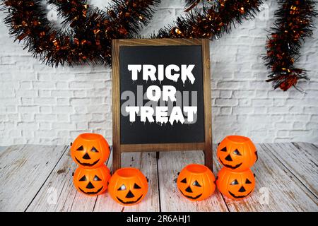 „Trick or treat“-Textnachricht mit Halloween-Dekoration auf der Tafel Stockfoto