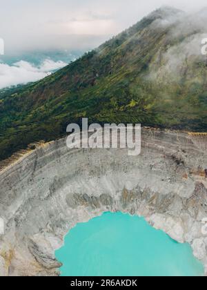 Der türkisfarbene Schwefelwassersee am Kawah Ijen Vulkan in Ost-Java, Indonesien, ist von Klippen umgeben. Stockfoto