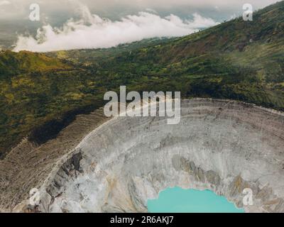 Der türkisfarbene Schwefelwassersee am Kawah Ijen Vulkan in Ost-Java, Indonesien, ist von Klippen umgeben. Stockfoto