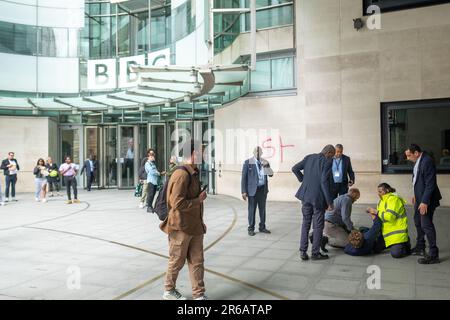 London - 23. Mai 2023: Ein Anti-BBC-Protestteilnehmer versucht, etwas auf das BBC Broadcasting House zu sprühen, und wird von der Sicherheit angegriffen. Stockfoto