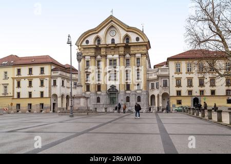 LJUBLJANA, SLOWENIEN - 7. MÄRZ 2023: Dies ist die Ursulinkirche der Heiligen Dreifaltigkeit und die Pestsäule auf dem Kongressplatz. Stockfoto