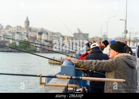 Istanbul, Türkei - 10. Mai 2023: Fischer werden mit ihrer Angelrute über der berühmten Galata-Brücke am Bosporus beim Fischen gesehen. Szene des täglichen Lebens Stockfoto