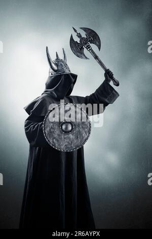 Krieger mit Hornhelm, doppelköpfiger Kampfaxt und rundem Schild im Dunkeln Stockfoto