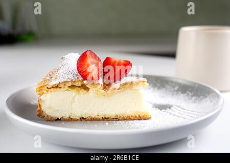 Ein Stück Kuchen Karpatka auf dem Teller. Traditioneller polnischer Kuchen Karpatka auf grauem Betonhintergrund. Cream Puff Cake 'Carpathian Mountain' mit Vanille Stockfoto