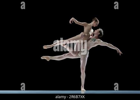 Unterstützung und Liebe. Junge talentierte Männer und Frauen, Balletttänzer in beigen Bodys, die vor schwarzem Studiohintergrund tanzen Stockfoto