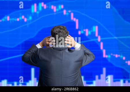 Der Stressaktienhändler schaut auf den Bildschirm und zeigt eine Grafik mit Kerzenleuchtern, die nach unten geht, Finanzmarktkollaps. Stockfoto