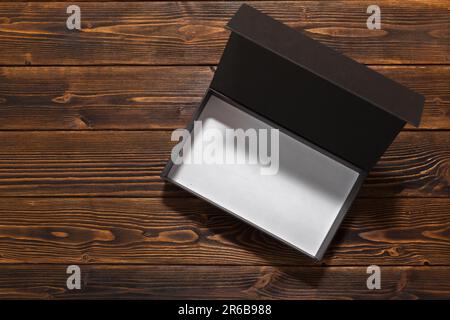 Leere schwarze offene Box auf Holzhintergrund Stockfoto