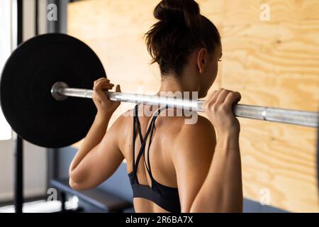 Rückansicht einer weissen jungen Frau, die im Fitnessklub die Klingel hebt, Kopierraum Stockfoto