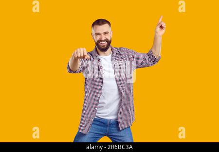 Fröhlich aufgeregter, prächtiger bärtiger Mann, 30s Jahre alt, trägt ein T-Shirt, das mit dem Finger auf den Arbeitsbereich zeigt. Stockfoto