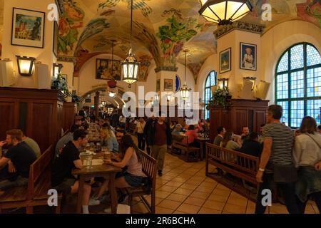 München, Deutschland - 04.07.2022: Berühmtes überfülltes hofbräuhaus traditioneller puddingkeller in München wunderschöne Deckenmalerei viele Menschen. Stockfoto