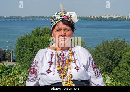 Dnipro, Ukraine - 13. September 2014: Eine ältere Frau in ukrainischer Nationalkleidung vor dem Hintergrund einer malerischen Aussicht auf den Fluss Dnipro auf dem Brigh Stockfoto