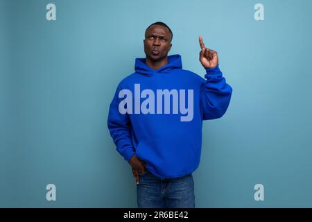 Ein hübscher, kurzhaariger Afrikaner in einem einfachen Hoodie demonstriert den Geist und die Einfallsreichtum einer Idee Stockfoto