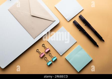 Flache Anordnung von schwarzen Stiften, Umschlägen, Büroklammern und Notizen mit Kopierbereich auf gelbem Hintergrund. Schulmaterial, Schreiben, Malen, Zeichnen, lear Stockfoto