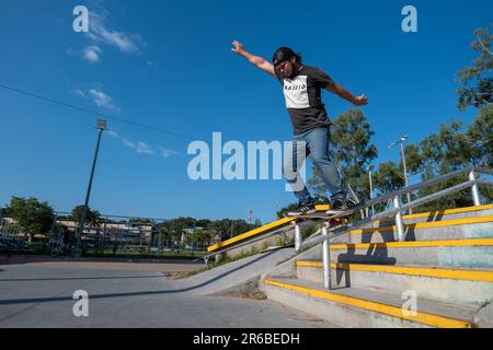 San Salvador, San Salvador, El Salvador - 11. November 2022: Der junge Brown man rutscht auf der Geländerschiene in einem Skate Park gegen Bäume Stockfoto