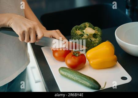 Frau schneidet reifes Gemüse für einen gesunden Salat Stockfoto