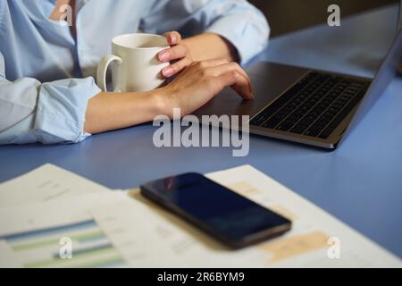Eine Frau, die ihren tragbaren Computer während der Kaffeepause benutzt Stockfoto