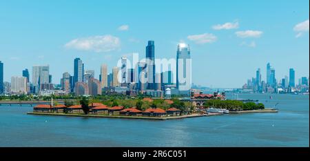 Ein Panoramablick auf Ellis Island, USA, seit der Bucht, mit der Innenstadt von Jersey City auf der linken Seite und Lower Manhattan, in New York City, ON Stockfoto