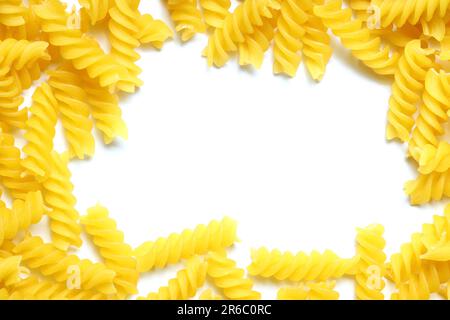 Ein Rahmen aus ungekochter Fusilli Pasta, verstreut auf weißem Tisch - Mock Up. Rohe und trockene Macaroni. Ungesunde und fettarme Lebensmittel. Italienische Kultur Stockfoto