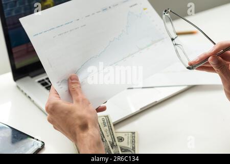 Schwarzer Geschäftsmann mit Smartphone, der Aktien- und Kryptowährungsmarkt im Büro überprüft. Afroamerikanischer Geschäftsmann, der das Internet mit nutzt Stockfoto