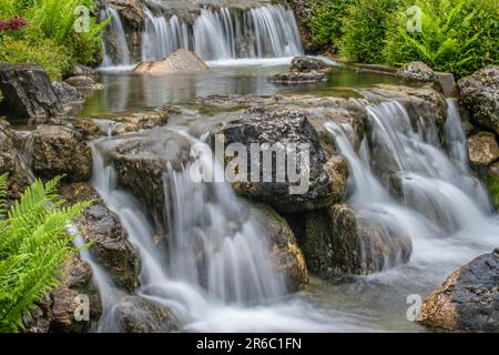 wien, österreich. 13. Mai 2023 bezaubernde Ruhe faszinierender Landschaftspark im japanischen Stil mit einem majestätischen Wasserfall, der von einer Steinmauer fällt, Gentlemen Stockfoto