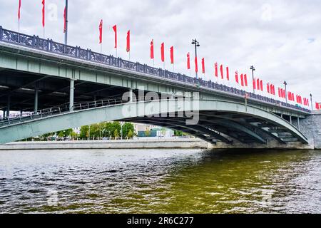 Große Steinbrücke über den Fluss Moskva, dekoriert mit roten Flaggen für den 9. Mai Stockfoto