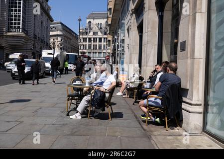 Menschen sitzen an einem heißen Sommertag während einer Mini-Hitzewelle im Juni 2023 auf Haymarket, West End of London, England, UK Stockfoto