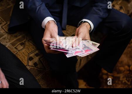 Ein Geschäftsmann im Anzug zählt zu Hause ukrainisches Geld. Stockfoto