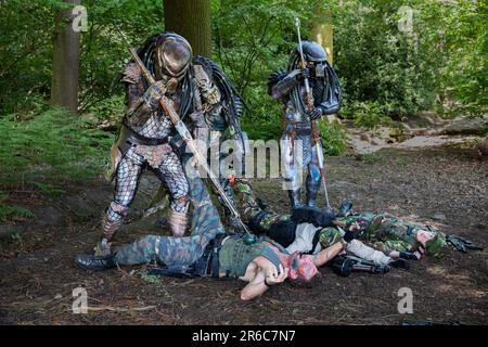 HARROGATE, GROSSBRITANNIEN - 3. JUNI 2023. Eine Gruppe Cosplay-Freunde, verkleidet als Alien Predator und Arnold Schwarzenegger aus der Filmreihe in Realistic CO Stockfoto