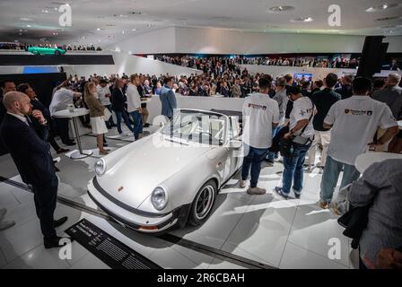 Stuttgart, Deutschland. 08. Juni 2023. Zahlreiche Gäste beobachten die Eröffnung der Sonderausstellung „Driven by Dreams“ während der feierlichen Veranstaltung zu 75 Jahren Porsche-Sportwagen im Firmenmuseum Stuttgart-Zuffenhausen. Kredit: Christoph Schmidt/dpa/Alamy Live News Stockfoto