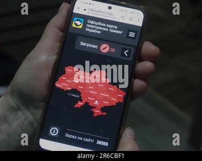 Kiew, Ukraine. 08. Juni 2023. Die Hand mit einem Smartphone mit einer offiziellen Karte der Flugwarnungen in der Ukraine zeigt, dass alle Regionen des Landes von 26 russischen Raketen bedroht sind. Kredit: SOPA Images Limited/Alamy Live News Stockfoto