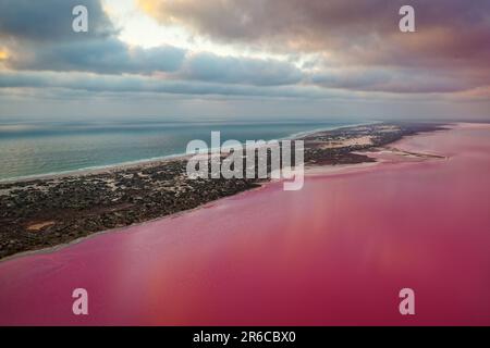 Pink Lake in Port Gregory in Westaustralien, farbenfrohes Wasser mit Bakterien und Algen, wunderschöner Kontrast zwischen dem blauen Ozean und dem rosa Wasser, Wolken Stockfoto