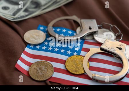 Golden Bitcoins Kryptowährung mit Handschellen auf Dollarscheinen. Konzept der digitalen Kriminalität, der Festnahme oder des Hacking. Handschellen Dollar und Bitcoins auf dem Tisch Stockfoto